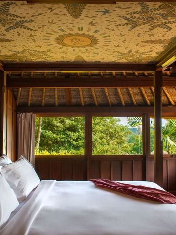Schlafzimmer des Amandari Hotels mit traditionellem Dekor und Blick ins Grüne