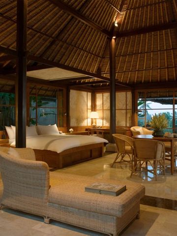 Luxuriöse Suite mit einem großen Doppelbett und gemütlichem Sofa im balinesischen Stil