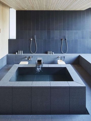 Luxuriöses Badezimmer mit großem Steinbad und Regenduschen