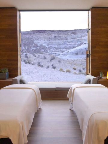 Wellnessraum mit zwei Massageliegen und großem Fenster mit Blick auf felsige Landschaft