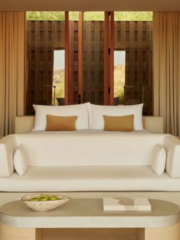 Elegante Suite mit beigem Sofa und großen Fenstern mit Vorhängen