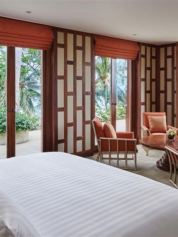 Geräumiges Zimmer mit Blick auf tropische Gärten und das Meer durch große Fenster