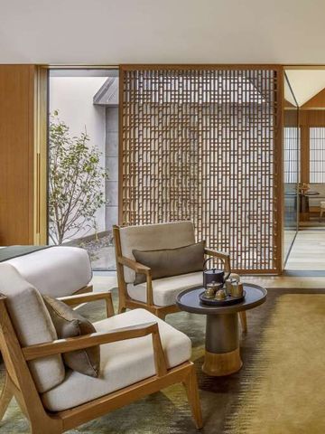 Elegantes Hotelzimmer mit Sitzbereich und asiatischem Dekor.