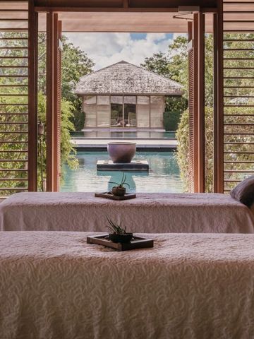 Zwei Massageliegen mit Ausblick ins Grüne und Pool im Spa-Bereich