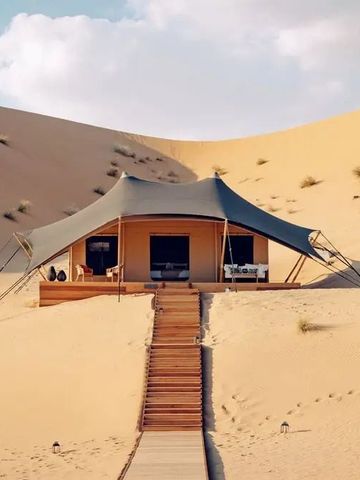 Luxuszelt unter blauem Himmel inmitten von Wüstendünen im AMAR LUXURY DESERT ECOLODGE