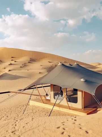 Luxuszelt in der Wüste mit Sanddünen im Hintergrund und blauem Himmel
