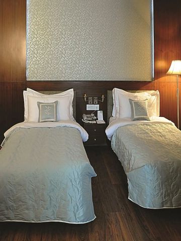 Hotelzimmer mit zwei Einzelbetten und moderner Beleuchtung