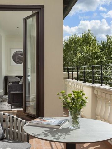 Terrasse mit Sitzgelegenheiten und Blick auf grüne Bäume unter blauem Himmel