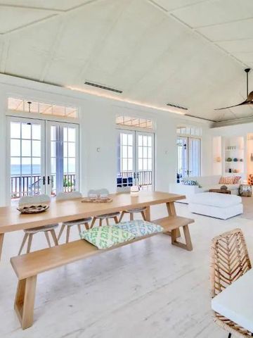 Offener Ess- und Wohnbereich mit Holztisch und Blick auf das Meer.