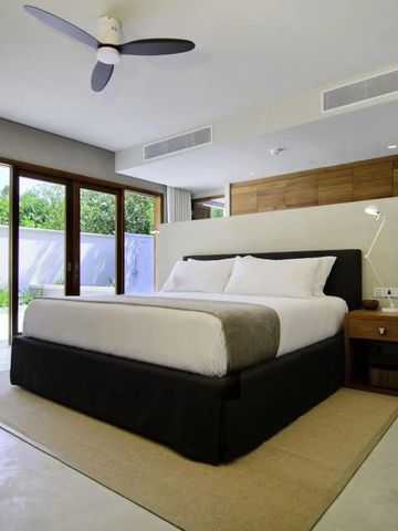 Helles Schlafzimmer mit großen Fenstern und Blick auf grünen Garten