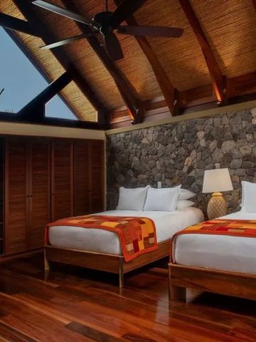 Zimmer mit zwei Betten und Steinwanddesign unter Holzdach