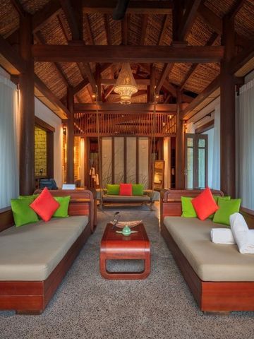 Geräumiger Wohnbereich mit Holzmöbeln und farbenfrohen Kissen im Hotel L'Alya