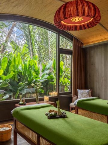 Massagebetten in einem luxuriösen Spa-Raum mit großen Fenstern und Blick auf tropische Pflanzen