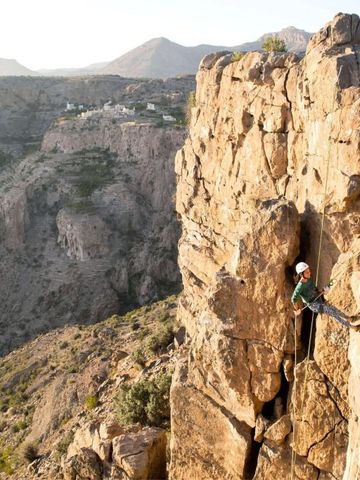 Kletterer an einer steilen Felswand mit Bergblick