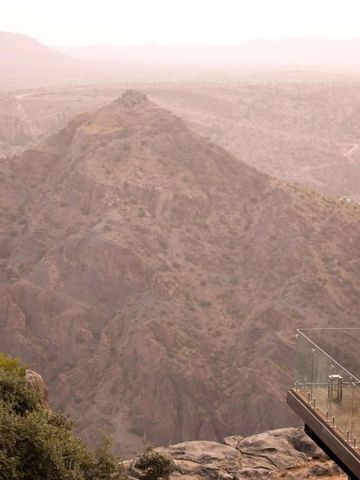 Spektakuläre Aussicht auf die Berge von einer Terrasse mit Glasgeländer.