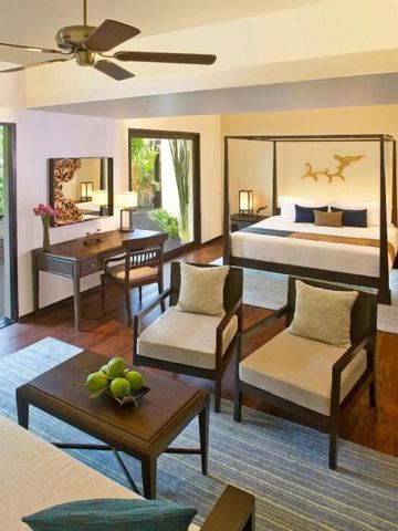 Geräumiges Zimmer mit Himmelbett und Wohnbereich öffnet sich zur Terrasse mit Gartenblick