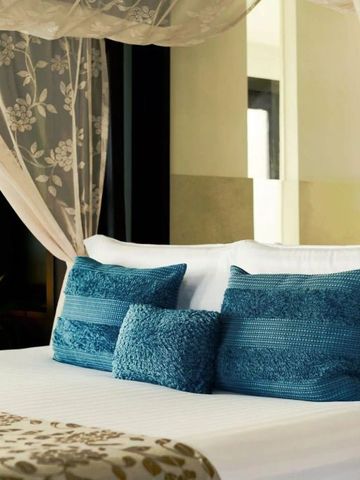 Gemütliches Bett mit dekorativen Kissen und Baldachin für luxuriösen Schlafkomfort