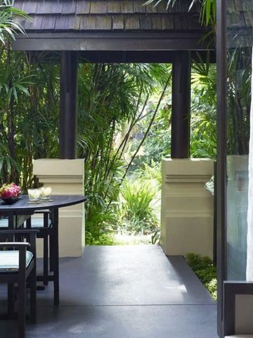 Private Terrasse mit Tisch, Stühlen und grüner tropischer Vegetation im Hintergrund.