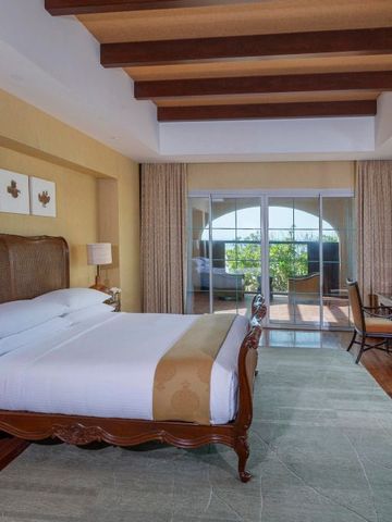 Elegantes Schlafzimmer mit Holzbalkendecke und Zugang zu einem Balkon