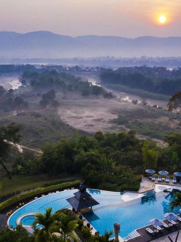 Sonnenuntergang über Landschaft mit Pool und Bergen