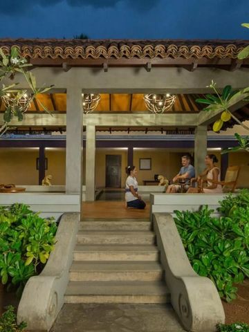 Gäste entspannen auf einer überdachten Terrasse mit üppigem Grün