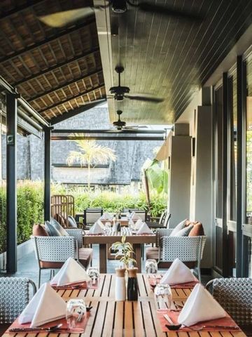 Gemütliche Open-Air-Terrasse mit gedeckten Tischen und üppigem Grün