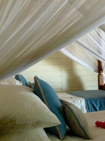 Himmelbett mit weißen Vorhängen und blauer Bettwäsche