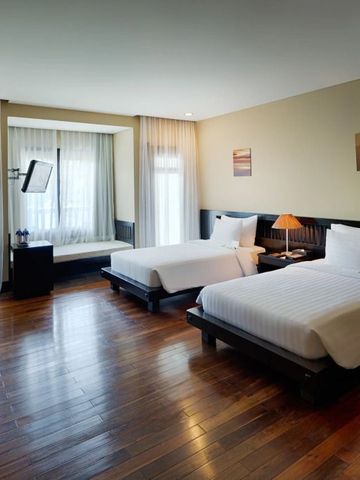 Modernes Hotelzimmer mit zwei Einzelbetten und großen Fenstern für viel Tageslicht.