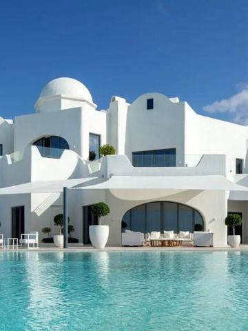 Strahlend weiße Villa mit großer Terrasse und Pool unter klarem Himmel