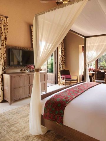 Helles Schlafzimmer mit Himmelbett und Blick auf den Garten