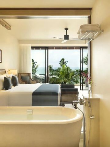 Geräumiges Schlafzimmer mit Badewanne und Blick auf Palmen