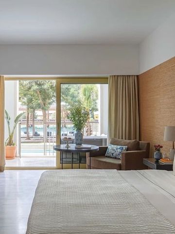 Geräumiges Hotelzimmer mit Bett und Blick auf den Poolbereich