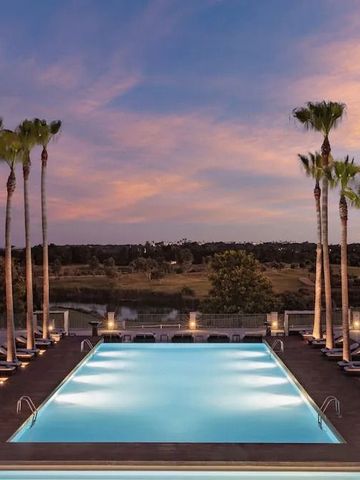 Beleuchteter Pool bei Sonnenuntergang mit Palmen und weitem Landschaftsblick