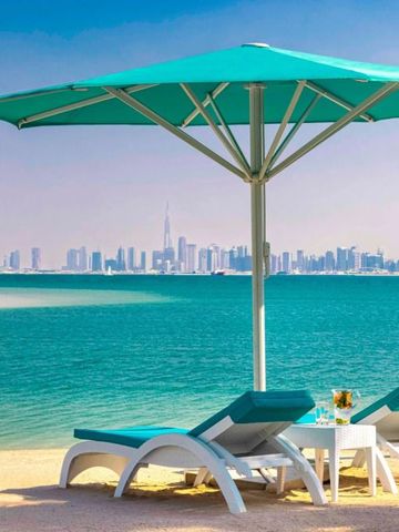 Strand mit Liegestühlen und Sonnenschirm, Dubai Skyline im Hintergrund