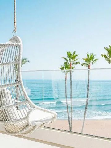 Balkon mit Hängesessel und Meerblick auf die Palmen und den Strand