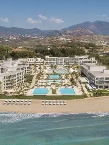 Gesamtansicht des Luxushotels am Strand mit Poolanlagen und Bergen im Hintergrund