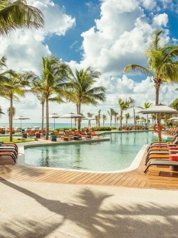 Einladender Hotelpool mit Liegen und Palmen unter klarem Himmel