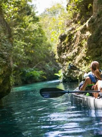 Zwei Personen im Kajak auf einem ruhigen, klaren Fluss zwischen Felsen