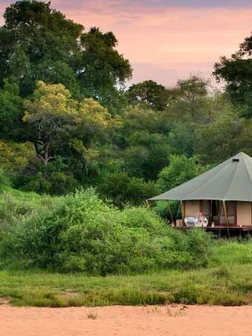 Luxuriöses Zelt in üppiger Landschaft bei Sonnenuntergang