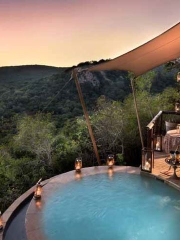 Runder Infinity-Pool mit Ausblick in die Natur bei Sonnenuntergang.