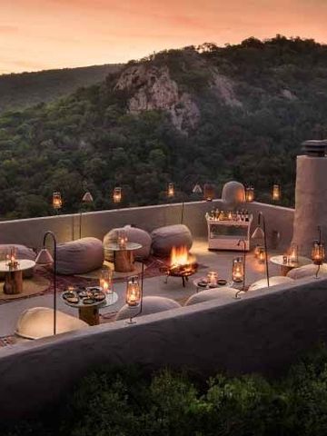 Dachterrasse mit gemütlichen Sitzgelegenheiten und Blick auf bewaldete Hügel.