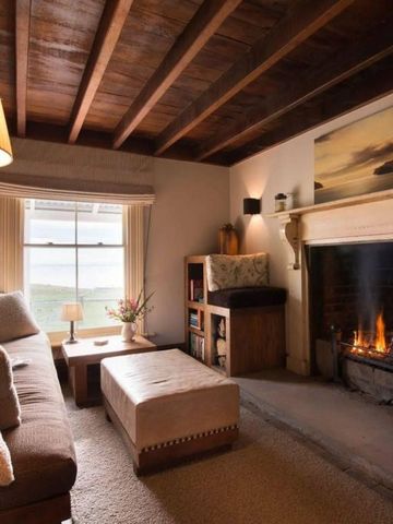 Gemütliches Wohnzimmer mit Kamin und Holzbalkendecke in einem Hotel.