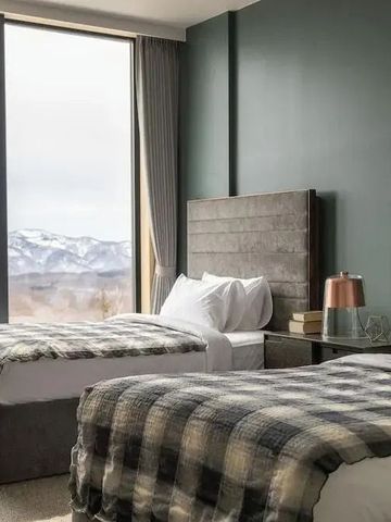 Zwei Einzelbetten in einem Zimmer mit Bergblick durch große Fenster