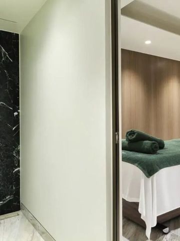 Luxuriöser Spa-Behandlungsraum mit dunkler Marmordusche und gemütlicher Liege