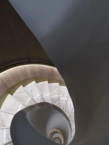 Geschwungene Treppe mit Marmor- und Holzelementen im Hotel