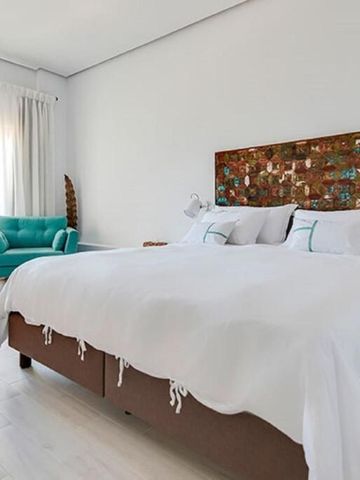 Geräumiges Zimmer mit buntem Kopfteilstück und türkisfarbenem Sessel