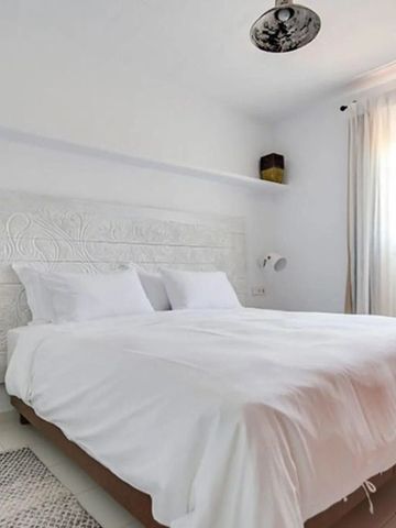 Helles Schlafzimmer mit dekorativem weißen Kopfteil und dezenten Details