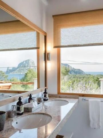 Badezimmer mit Panoramafensterblick auf Küstenlandschaft und modernen Armaturen.