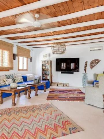 Gemütliches Wohnzimmer mit Holzbalkendecke und bunten Teppichen, komfortablen Sofas und großem TV