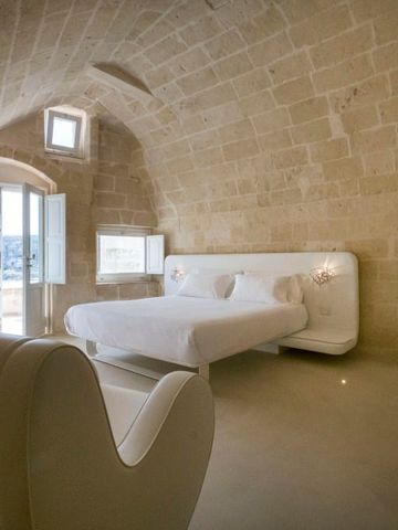 Luxuriöses Hotelzimmer mit weißer Bettwäsche und rustikalen Steinwänden